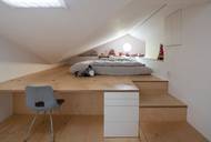 Spaní pro dítě je na podestě, která pozvolna přechází v pracovní stůl.