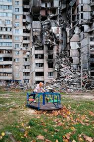 Olga Kovalova: Malá Polina si hraje na hřišti mezi zničenými budovami v nejpoškozenější čtvrti Charkova na Ukrajině (2. listopadu 2022). Ukázka z výstavy fotografií Bojují i za nás v chebské Galerii 4.