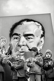 Leonid Iljič Brežněv na transparentu v prvomájovém průvodu roku 1979. Brežněv byl generálním tajemníkem Ústředního výboru Komunistické strany Sovětského svazu (1966-1982) a předsedou prezídia Nejvyššího sovětu (1977-1982). Brežněvova doktrína omezené suverenity řídila sovětskou zahraniční politiku od roku 1968 až do Gorbačovovy perestrojky. Podle ní měl Sovětský svaz právo ovlivňovat i s použitím síly vývoj v libovolné zemi východního bloku, pokud zde hrozilo odvrácení od socialismu ke kapitalismu. Konkrétním příkladem její aplikace byla okupace Československa v srpnu 1968.