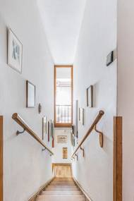 Z přízemí vedou do patra úzké, prosvětlené schody s obrazy a fotografiemi na stěnách.