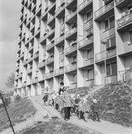 Děti z mateřské školky v doprovodu učitelek kráčí okolo tehdy nově postavených panelových domů. Snímek z roku 1975.