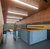 Fasáda je v kontrastu s tmavě pigmentovaným modřínovým obkladem stěn a podhledu ve vstupní části a v plavecké hale.