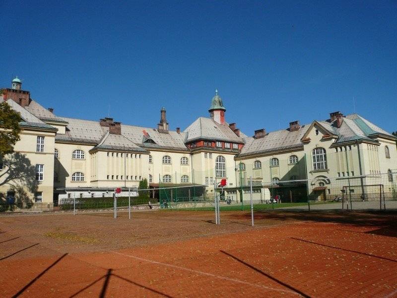 Krkonošské gymnázium a SOŠ, které má budovu ve Vrchlabí a Hostinném, má za sebou změnu na ředitelském postu, ale tím změny nekončí! Zlepšit formu výuky, zapojit žáky formou projektové výuky nebo zmodernizovat prostory Krkonošského gymnázia ve Vrchlabí či inovovat výuku v Hostinném. To je malý výčet toho, co v následující době gymnázium čeká a za čím si nový ředitel stojí.    Nový ředitel gymnázia Jan Kletvík není ve škole nováčkem, dobře zná místní poměry a za poslední rok se mu povedlo i skvěle navnímat situaci na škole. Velmi dobře si tak uvědomuje nutnost posunu gymnázia novým směrem. Do školy se snaží zavést několik novinek a zároveň posunout dopředu stávající projekty, které vnášejí do výuky nové možnosti pro žáky, a navíc vycházejí z toho, co žáky baví.   Jedním takovým projektem je program Sapere aude pro nadané a motivované, který se rozběhl v roce 2023 a nyní se rozšiřuje. “Například žáci, kteří se připravují na přijetí na UMPRUM, potřebují mít čas na přípravu svého portfolia, mají od nás k dispozici výtvarný ateliér a příprava probíhá místo výuky. Stejně tak i žáci, kteří jsou nadšení ornitologové, pracují na projektu, kde se věnují pozorování ptactva, mohou místo hodin ve škole jít na pozorování. Myšlenka je taková, aby se žáci v čase, který je určen pro školu, věnovali hlavně tomu, na co se chtějí zaměřit a co pro to potřebují vytvořit. Škola je ráda podpoří,” komentuje ředitel školy Jan Kletvík. Pod heslem „Každý může uspět, ať už zvolí jakoukoliv cestu” nyní na škole v rámci inovace dávají prostor všem, kteří mají zájem se posouvat v tom, co je baví. Jedná se o obdobný přístup, který funguje na škole už delší dobu – a to jsou úlevy od školy pro sportovce.    Velkou inovací je projektová výuka. Na škole nyní probíhá vzdělávání učitelů na téma „Jak úspěšně vytvářet projektovou výuku a propojovat jednotlivé předměty". Učitelé v tom mají dobrou podporu od pana Mgr. Miroslava Slowika, Ph.D., experta na projektovou výuku působícího na Technické univerzitě v Liberci. Pravidelně jezdí na školu a školí nejenom, jak projektovou výuku tvořit, ale i jak přistupovat k žákům, jak je motivovat nebo dávat zpětnou vazbu. Cílem je, aby učitelé byli schopni sami vytvořit projektový týden, kdy žáci zpracují určité téma do detailu, a to téma bude integrovat učivo z několika předmětů najednou. Například nyní se chystá jednodenní projekt na téma invaze. Jedna skupina to řeší z geopolitického pohledu, druhá skupina botanicky přes invazivní rostliny, a třetí jazykovým způsobem. Navzájem zkoumají, co mají jednotlivé prvky společného. Časem by měl projektový týden vyústit v integrovaný pravidelný předmět, například každé úterý dopoledne. „Chtěli bychom docílit toho, aby vznikl projekt, kde dojde k určité evaluaci a student dostane i zpětnou vazbu, proč uspěl nebo neuspěl a co se mu podařilo. Vidím v tom posun i ve vnímání žáků a jejich zapojení do výuky, což je může aktivovat a třeba jim i ukázat směr, kterým se mají v životě vydat,” dodává Jan Kletvík.    V neposlední řadě se gymnázium snaží více otevřít veřejnosti a žákům ukázat, jak to reálně funguje v místních firmách. Proto se Krkonošské gymnázium spojilo s několika místními odborníky z různých firem a zapojilo je do výuky. Ve výukovém plánu se tak objevuje třeba roční seminář mikroekonomie, kdy na gymnázium dochází pan Vrbata, ředitel společnosti Kablo Vrchlabí, nebo bloková výuka makroekonomie, kdy je například měsíc věnován bankovnictví nebo veřejným rozpočtům. A tímto způsobem je sestaveno několik témat, a to především v posledním ročníku, kdy mají studenti profilovanou výuku. „Z celkových 30 hodin si mohou 14 hodin zaplnit předměty, které je připraví na je