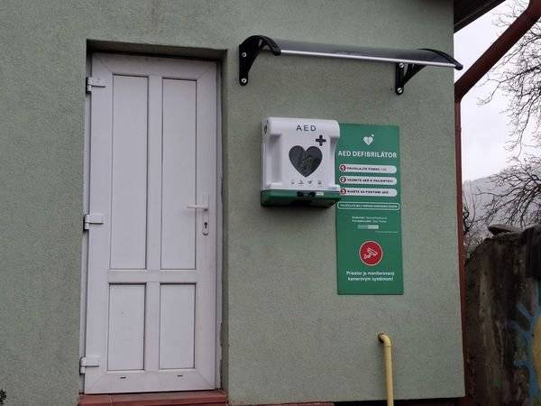 Na budove obecného úradu v externej skrinke je od 18.11.2024 uložený automatický defibrilátor AED vrátane pomocného setu prvej pomoci. Každá obec nad 500 obyvateľov podľa zákona o obecnom zriadení (§3 ods.5) je povinná zabezpečiť na verejne prístupnom mieste funkčný automatický externý defibrilátor. Skrinku, v ktorej je uložený defibrilátor otvoríte stlačím tlačidla OPEN a defibrilátor sa Vám vysunie smerom dole. Skrinka, v ktorej je AED uložený je osvetlená a dobre viditeľná aj v noci. Priestor, v ktorom je AED uložený je monitorovaný kamerovým systémom. Obec Rudlov zakúpila defibrilátor prostredníctvom spoločného nákupu 29 obcí v Združení miest a obcí vranovského regiónu od spoločnosti SPENCER MEDICAL s.r.o.  Defibrilátor je zaregistrovaný na tiesňovej linke 155 a operátor Vás vie k prístroju AED navigovať a pomôcť Vám pri jeho použití.    Defibrilátor vie použiť aj nezaškolená osoba. V obci budete mať vyškolených 5 osôb, ktorých v prípade zásahu bude kontaktovať tiesňová linka 155 a prvú voľnú preškolenú osobu vyšle na pomoc k miestu zásahu.