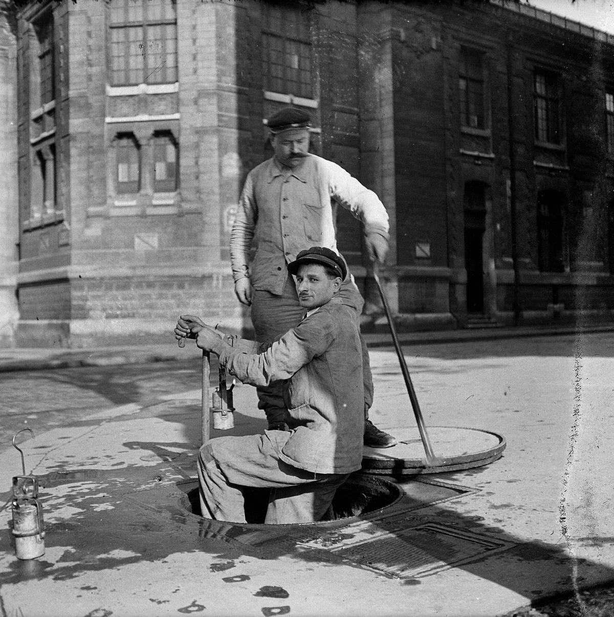 Čištění kanalizací zahrnuje odstraňování usazenin a nečistot z kanalizačních sítí pomocí speciálních nástrojů a techniky. Pracovníci čelí riziku kontaktu s nebezpečnými chemikáliemi a biologickým odpadem. Práce se odehrává v uzavřených prostorách s minimem ventilace a vyžaduje ochranné pomůcky.
Na snímku jsou dělníci kanalizace při práci v ulicích Paříže, 1943.