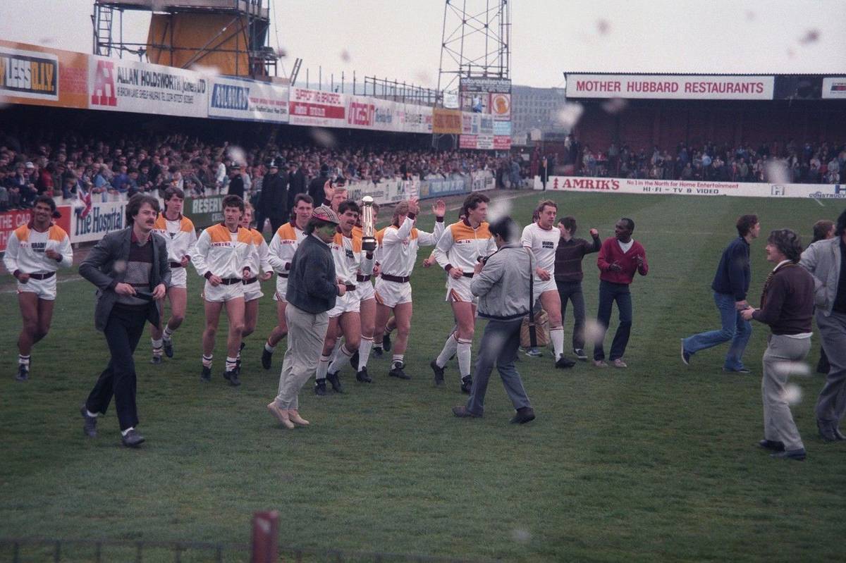 Fotografie zachycuje moment před začátkem utkání mezi Bradford City a Lincoln City. Hráči domácího týmu právě obíhají stadion s trofejí za vítězství ve čtvrté divizi, kterou si zajistili několik kol před koncem sezony. Utkání mělo být oslavou úspěšného ročníku, přičemž hlavní tribuna byla výjimečně zaplněná – mnoho fanoušků si přišlo připomenout návrat do vyšší soutěže. V tu chvíli ještě nikdo netušil, že zhruba o půl hodiny později stadion zachvátí požár s tragickými následky.