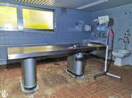 Okresní nemocnice: Průzkum, který začal nenápadně a skončil překvapením

Bylo brzké odpoledne a skupina urbexerů měla za sebou už několik povedených lokalit. Auto zaparkovali přímo před hlavním vchodem do staré okresní nemocnice. O objektu neměli žádné bližší informace, jen útržkovitou zprávu, že by se ve sklepních prostorách mohla nacházet pitevna. Bez dalších očekávání začali hledat vstup.

Ten našli překvapivě rychle – otevřené okno přímo vybízelo k tichému průniku dovnitř. Budova byla překvapivě dobře zachovalá, což v kontrastu s jednoduchostí vstupu působilo podezřele. Po seskoku se členové týmu rozdělili, aby co nejrychleji prozkoumali patro. Cílem bylo jediné: najít pitevnu. Procházeli prázdné pokoje, míjeli řady nemocničních postelí, ale kýžené místo stále nikde.

U recepce je však zarazil blikající displej zabezpečovacího systému. To nebylo dobré znamení. Okamžitě se vydali zpět k oknu, kterým přišli, a přesunuli se do auta. Rozhodli se počkat – pokud se v okolí nikdo neobjeví, zkusí to znovu. Minuty ubíhaly a s nimi pomalu opadával i stres. Když se vše zdálo klidné, vrátili se zpět do budovy, tentokrát do druhého křídla.

Právě tam, už po několika metrech, narazili na schodiště vedoucí do suterénu. Bylo jasné, že tady to musí být. Ostatní členy svolali a všichni se pomalu a opatrně vydali dolů. A i když pitevnu očekávali, její skutečný nález jim přece jen vyrazil dech: kompaktní místnost s pitevním stolem a hned vedle další prostor se zachovalými chladicími boxy na těla. Byla to přesně ta lokalita, kterou jedna ze členek týmu bezvýsledně hledala už několik dní – a celou dobu ji měla ve své mapě.

Nervozita z aktivní zabezpečovačky byla ale stále přítomná, a tak focení probíhalo rychle, ale důsledně. Nebyl čas vracet se pro profesionální fotoaparát – každý okamžik byl cenný, a nikdo nevěděl, zda někdo nepřijede. Snímky tedy vznikly na mobil. K autu se skupina vracela o desítky minut později – nadšená, ohromená a s pocitem, že právě zažila něco nečekaně silného.