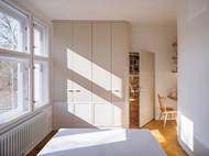 Celý byt je sjednocen dubovou podlahou a klidnou paletou tónů v bílé a béžové. Jemný detail a poctivé řemeslo tu hrají významnou roli.