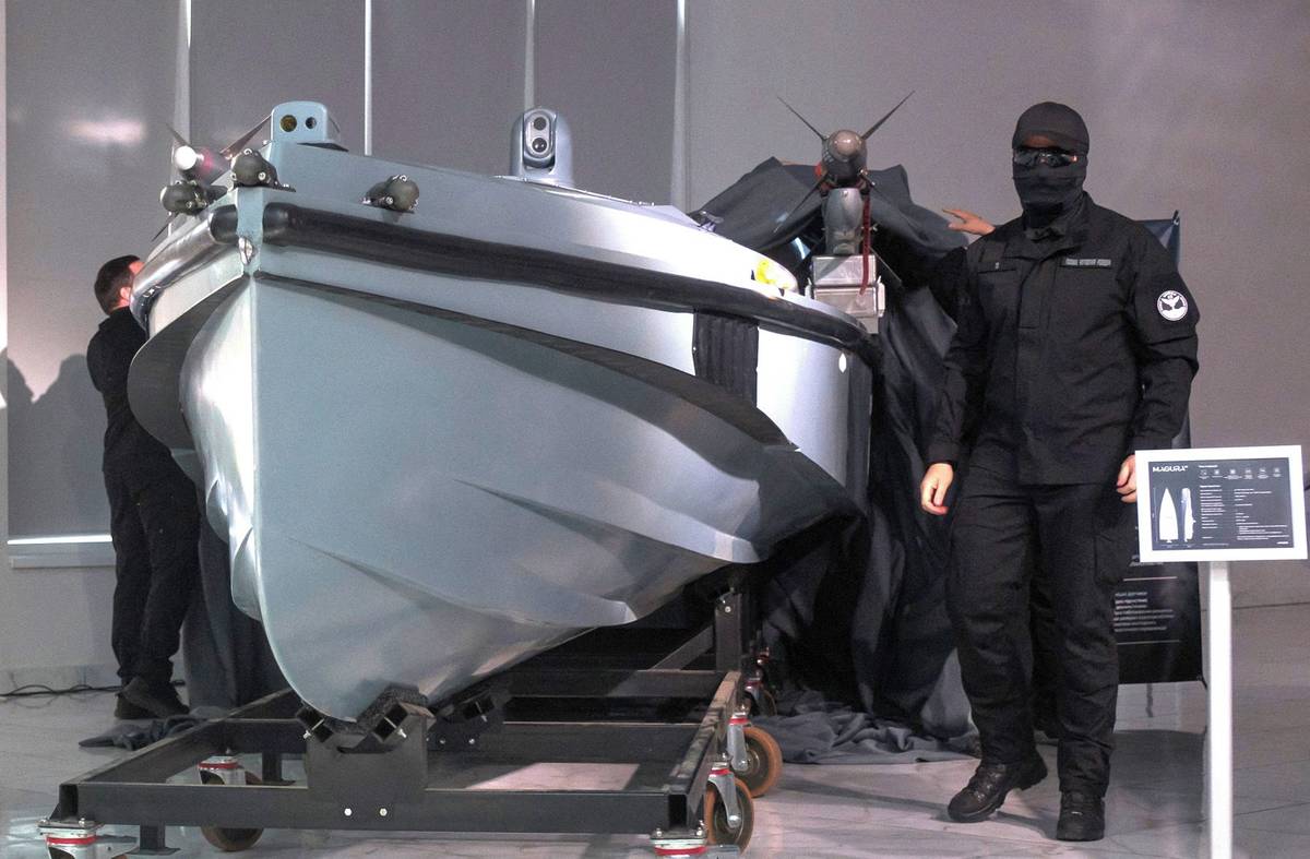 Příslušníci ukrajinské vojenské rozvědky snímají plachtu z námořního dronu Magura V7 během jeho představení na utajeném místě na Ukrajině.