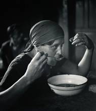 Žena s šátkem na hlavě jí z misky během stávky stavebních dělníků, 1938.