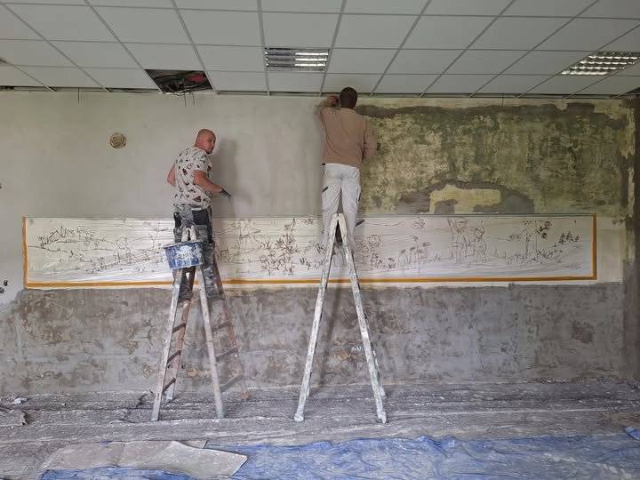 Při rekonstrukci sálu v budově OÚ Krásná byla pod strženým dřevěným obložením objevena částečně zachovalá nástěnná malba, která určitě pochází z dob, kdy úřad býval školou a sál školní třídou. Malířům se podařilo „obraz“ do jisté míry zrestaurovat, nicméně v zachovalých částech se nenalézá žádný rok vzniku ani žádné jméno autora. Letmé vzpomínky jedné z bývalých žaček školy nasvědčují prozatím tomu, že se jedná o dílo minimálně z přelomu 60. a 70. let 20. století, může však být ještě mnohem starší. Prosíme tímto, aby se nám na úřad jakoukoliv formou ozvali další žáci dřívější školy, kteří by si snad na výjev krajiny s dětmi na stěně třídy vzpomněli nebo dokonce byli schopni nalézt relevantní fotografie či jiné dokumenty svědčící o skutečném stáří tohoto hodnotného krásenského pokladu.