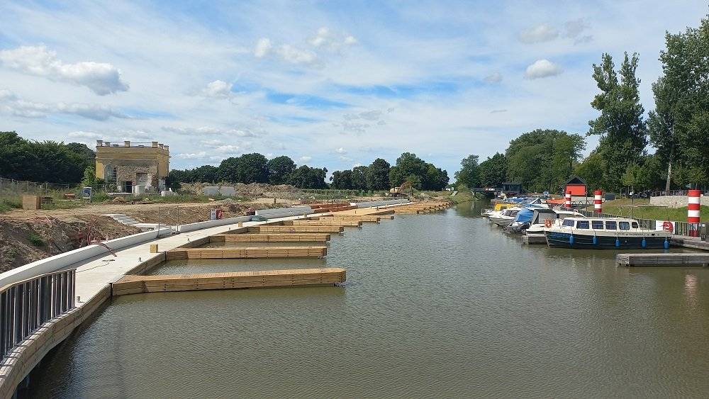 Od pondělí 18. srpna mohou turisté využívat tři desítky nových stání, které Ředitelství vodních cest ČR uvedlo do provozu v nově rozšířené části veřejného přístavu ve Veselí nad Moravou. „Jsem rád, že se nám povedlo pro veřejnost zprovoznit novou část přístavu už nyní, ještě v průběhu plavební sezóny. Přístav ve Veselí nad Moravou je velmi oblíbený a my tak můžeme vyjít vstříc turistům, kteří tráví dovolenou plavbou po Baťově kanálu a mají zájem zde se svou lodí zastavit,“ říká Lubomír Fojtů, ředitel Ředitelství vodních cest ČR, provozovatele a investora přístavu, a dodává: „Nyní začíná sloužit plavidlům první ze dvou etap rozšíření přístavu. Po kompletním dokončení bude mít přístav celkovou kapacitu 81 míst a stane se největším veřejným rekreačním přístavem nejen na Baťově kanálu, ale v celé České republice.“ Práce na další etapě přístavu nebylo zatím možné zahájit, neboť spolek Děti Země – Klub za udržitelnou dopravu podal správní žalobu ke Krajskému soudu v Brně proti vydaným výjimkám ze zákazů u zvláště chráněných druhů rostlin a živočichů a Krajský soud přiznal této žalobě odkladný účinek. Do doby definitivního rozhodnutí soudu tak není možné v dalších stavbách pokračovat. „Po chladnější první polovině prázdnin nastoupilo léto v plné zbroji a Baťův kanál je ideálním místem pro horké letní dny. Těší mě, že stavba tak rychle pokročila a začíná už teď sloužit občanům i návštěvníkům města,“ říká Petr Kolář, starosta Veselí nad Moravou. „Na stavbě nás ještě čekají dokončovací práce, včetně zprovoznění odběrných sloupků elektřiny a vody. Tato zařízení v nové části přístavu jsou zatím mimo provoz a fungovat budou až od nové plavební sezóny po dokončení veškerých rozvodů. Stání plavidel na nových polohách je možné bez omezení, jen nejsou k dispozici břehové přípojky,“ říká Vladimír Dvořák, ředitel společnosti Inženýrské a dopravní stavby Olomouc, a.s., zhotovitele stavby. Břehová hrana v jižní části přístavu byla posunuta směrem k nově vznikajícímu vinařskému areálu. Byly vybudovány 3 pevné přístavní hrany s kolmými plovoucími výložníky vymezujícími jednotlivá stání pro plavidla. V rámci přístavu vznikly také dvě platformy pro odpočinek navazující na pevná mola a stupně na sezení. Zhotovitelem stavby byla společnost IDS – Inženýrské a dopravní stavby Olomouc a.s. Náklady ve výši 78,4 mil. Kč bez DPH financoval Státní fond dopravní infrastruktury.   O Ředitelství vodních cest ČR ŘVC ČR je organizační složkou státu, zřízenou Ministerstvem dopravy k zabezpečení přípravy a realizace výstavby a modernizace dopravně významných využívaných vodních cest a dalších staveb nutných pro provoz na vodních cestách. Ředitelství vodních cest ČR rovněž provozuje veřejné přístavy a přístaviště i remorkér BESKYDY.