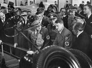 Ferdinand Porsche (vpravo v obleku) s říšským kancléřem Adolfem Hitlerem nad podvozkovou skupinou nového lidového KdF.