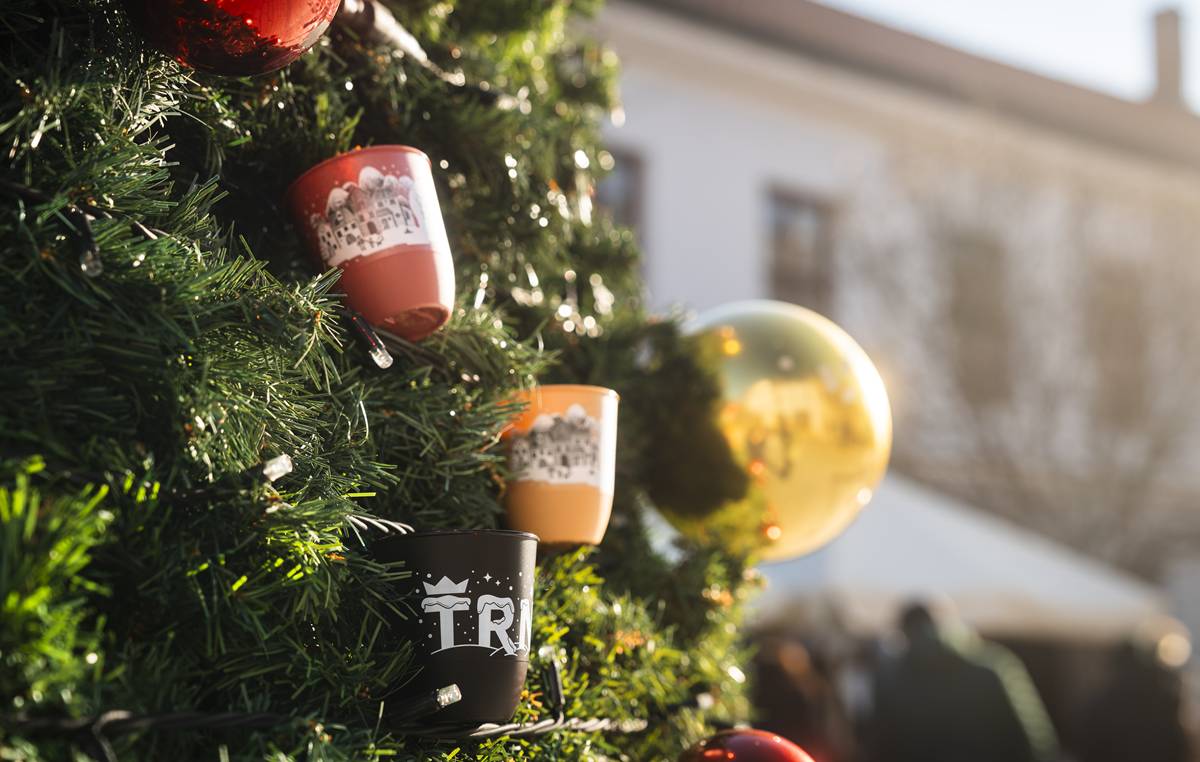 Srdečne vás pozývame do krásne vyzdobeného centra Trnavy. Počas Adventu v Trnave vás tu od dnes až do 22. decembra čakajú adventné trhy a bohatá nádielka podujatí.  Začíname o 17.30 h alegorickým sprievodom s lampášikmi, ktorý privedie svetlo až k vianočnému stromčeku na Trojičnom námestí. Príďte to zažiť na vlastné oči. :-) Na adventných trhoch si aj tento rok vychutnáte vianočnú medovinu a iné tekuté dobroty zo špeciálnych zálohovaných pohárov. Každý zapojený stánok bude označený piktogramom, ktorý návštevníkom napovie, že sa v ňom poháre predávajú aj vykupujú. Ešte krajšie poháriky a lepší systém Malé priehľadné s objemom 0,1 l aj dvojdecové čierne, béžové a bordové poháre vám vydajú za zálohu vo výške 2 €. Tá ostala proti vlaňajšku nezmenená; čo sa však navýšilo, je počet pohárov. V obehu ich bude až 100 000, pričom viac než štvrtina z nich ponesie originálny trnavský motív. Ak sa vám takýto pohárik zapáči, môžete si ho nechať.  Vrátiť sa bude dať v zapojenom stánku s nápojmi alebo výkupných stánkoch. Tie budú oproti vlaňajšku až dva – jeden bude otvorený denne od 13.00 do 22.30 h a cez víkendy k nemu pribudne medzi 18.00 a 22.30 h aj druhý. Novinkou bude tiež možnosť vrátiť vo výkupných stánkoch zálohu okrem hotovosti aj bezhotovostne – príde vám teda priamo na účet po priložení platobnej karty, mobilu či iného zariadenia s bankovým čipom. Hygiena je samozrejmosťou Umývanie pohárov zabezpečuje certifikovaná spoločnosť, ktorá garantuje hygienickú čistotu. Predajcovia sú povinní naliať vám nápoj vždy do nového pohára. Ak si prinesiete vlastný z domu, nápoj načapujú do čistého opätovne použiteľného pohára a prelejú ho do vášho. V minulom roku bola jednému predajcovi udelená pokuta za porušenie pravidiel a spoločnosť, ktorá systém prevádzkuje, sa z nej rozhodla venovať sumu 1 000 eur Azylovému domu Tamara v Trnave. Na zdravie a na dobrú vec Ak budete mať chuť spraviť počas adventných trhov dobrý skutok, nie je nič jednoduchšie. Dvojeurovú zálohu budete môcť venovať organizáciám z regiónu, ktoré sa venujú pomoci druhým. Pohárik môžete vrátit buď priamo v charitatívnom stánku, kde budú predávať svoje výrobky, alebo v jednom z dvoch výkupných stánkoch. Celá hodnota zálohy sa premení na priamy finančný dar pre pomáhajúce organizácie. Ich zoznam a harmonogram predaja nájdete na portáli advent.trnava.sk. Ďalší krok k udržateľnosti Do systému sa po novom zapoja aj stánky na súkromnom pozemku z bočnej strany ROH, ktoré sa ním vlani inšpirovali a z papierových pohárov prejdú na zálohované. Vďaka spoločnej snahe budú adventné trhy opäť bližšie k udržateľnosti.  Rok 2024 priniesol povzbudivé výsledky – aj napriek vyššej účasti kleslo množstvo odpadu vyprodukovaného počas podujatia. Znížili sa aj náklady na odpadové hospodárstvo a likvidáciu odpadu, čo potvrdzuje, že systém zálohovaných pohárov má skutočný environmentálny aj ekonomický prínos.