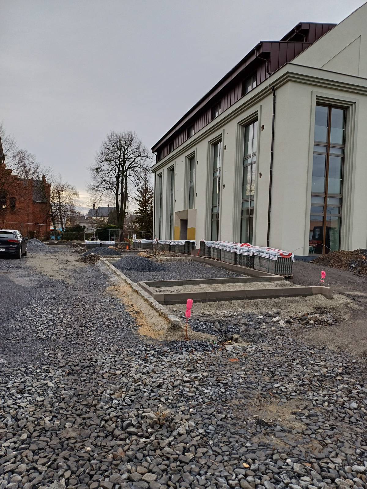 Výstavba nového parkoviště u Červeného kostela a sýpky přinese potřebnou úlevu v lokalitě, kde místa pro parkování aut dlouhodobě chybí. Během prací však dělníci narazili na zásadní problém: plynovod uložený v nedostatečné hloubce, který neodpovídá bezpečnostním normám. Tento nález realizaci prodlouží, bez přeložky plynovodu není možné výstavbu zpevněných ploch bezpečně dokončit. Město nyní koordinuje nezbytné práce se společností GasNet.   Zhotovitel EUROVIA CZ přerušila stavbu od 15. prosince. Přeložka plynovodu by měla být realizována letos na jaře, poté budou práce pokračovat podle upraveného harmonogramu: stavební práce do  30. 6., krajinářské úpravy do 31. 7., kompletní předání díla do 10. 8. 2026.   „Zjištěná kolize s plynovodem je komplikace, která se u staveb pod zemí může objevit, ale není možné ji obejít. Musíme postupovat bezpečně a v souladu s technickými normami. Upravené termíny nám umožní stavbu dokončit kvalitně a bez rizik. Obyvatelé si sice na nové parkoviště počkají o něco déle, ale výsledkem bude bezpečný, funkční a dlouhodobě přínosný prostor pro celou lokalitu s 15 novými parkovacími místy,“ uvedl místostarosta Václav Škvain.   Dotčená část města se dlouhodobě potýká s nedostatkem parkovacích kapacit, a to jak pro rezidenty, tak pro návštěvníky okolních míst – kostela, hřbitova či centra města. Dočasné přerušení stavby prodlouží období omezených možností parkování v území. Po dokončení ale nové parkoviště poskytne výrazně vyšší komfort, usnadní pohyb v lokalitě a zlepší dostupnost služeb i místních institucí.    #hlucin #mestohlucin #parkovacimista