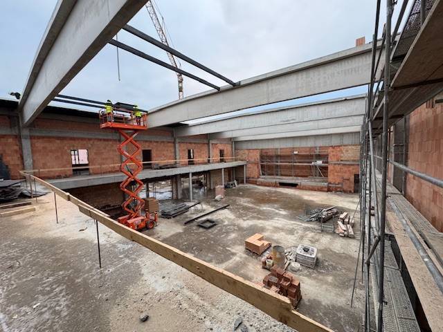 V tomto týdnu byl na programu další kontrolní den za účasti zástupců investora, projekční firmy, architektů i zhotovitele stavby. I když nás v lednu na devět dní přibrzdilo mrazivé počasí, harmonogram to neovlivnilo a stavba výrazně pokročila. Aktuálně už je dokončena hlavní nosná konstrukce – budova má už svou finální podobu i objem. Pokračuje zdění vnitřních příček, zahájeny byly práce na rozvodech vody, kanalizace a elektřiny a zároveň se postupně upřesňuje a vzorkuje vnitřní vzhled budovy – oken, dveří, detailní podoba schodišť, podlah a akustických prvků hlavního sálu.  Nový Obecní dům na jednom místě zajistí kvalitní zázemí pro městskou knihovnu, informační centrum, základní uměleckou školu s moderními akustickými učebnami a menším koncertním sálem, velký multifunkční sál s kapacitou 527 míst, určený pro široké spektrum kulturních a společenských akcí. Projekt v hodnotě bezmála 166 milionů Kč bez DPH realizuje společnost MSO servis spol. s r. o. Kyjov. Stavba by měla být dokončena do 600 kalendářních dnů od zahájení prací v červnu loňského roku. Na dotacích se zatím podařilo na výstavbu Obecního domu získat 38 milionů korun, další dotace se budeme snažit získat.  Obecní dům bude novým srdcem Vracova – místem pro vzdělávání, kulturu i společenská setkávání.  V přiložené fotogalerii si můžete prohlédnout, jak to na stavbě aktuálně vypadá. Vizualizaci nového Obecního domu si můžete prohlédnout zde: https://youtu.be/oaZfkYqKkVs