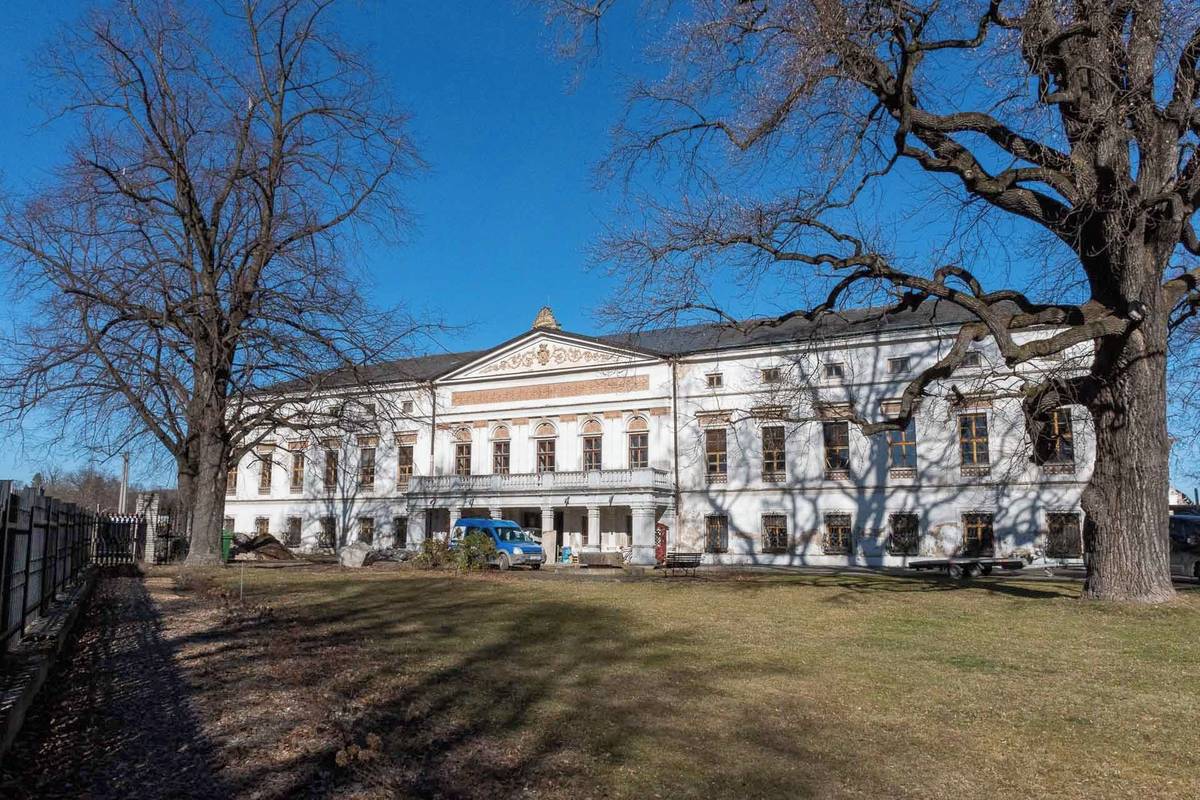 Je čtvrtek 3. března 2026. Polední slunce dopadá na jižní průčelí budovy zámku a stíny větví se zkracují. Jaro sice oficiálně ještě nezačalo, ale počasí tomu už napovídá. Na stavbě je to znát.  Stavební práce pokračují v lepší náladě a atmosféra je uvolněnější než v uplynulých zimních týdnech.