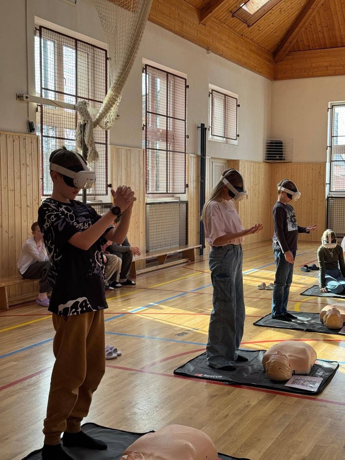 V minulých dnech proběhla v Tyršově základní a mateřské škole velmi zajímavá a přínosná vzdělávací akce „První pomoc s virtuální realitou“. Nejstarší žáci si vyzkoušeli realistické situace, ve kterých bylo potřeba rychle a správně reagovat při záchraně lidského života. S pomocí brýlí pro virtuální realitu se ocitli v situaci, kdy museli pomoci člověku, který nedýchá, a pod vedením virtuálních instruktorů si prakticky vyzkoušeli správný postup první pomoci. Pro děti to byl nejen poutavý, ale především velmi užitečný zážitek – je to zkušenost, která může jednou pomoci zachránit lidský život. Zájem byl tak velký, že si tuto dovednost vyzkoušeli také dospělí z řad pedagogického i technického personálu školy. Velmi si vážíme podpory Městského obvodu Plzeň 8 – Černice, který financováním této akce umožnil našim dětem zažít moderní a smysluplné vzdělávání v praxi. Děkujeme za dlouhodobou podporu školy a za to, že společně můžeme dětem přinášet zkušenosti, které mají skutečný význam.