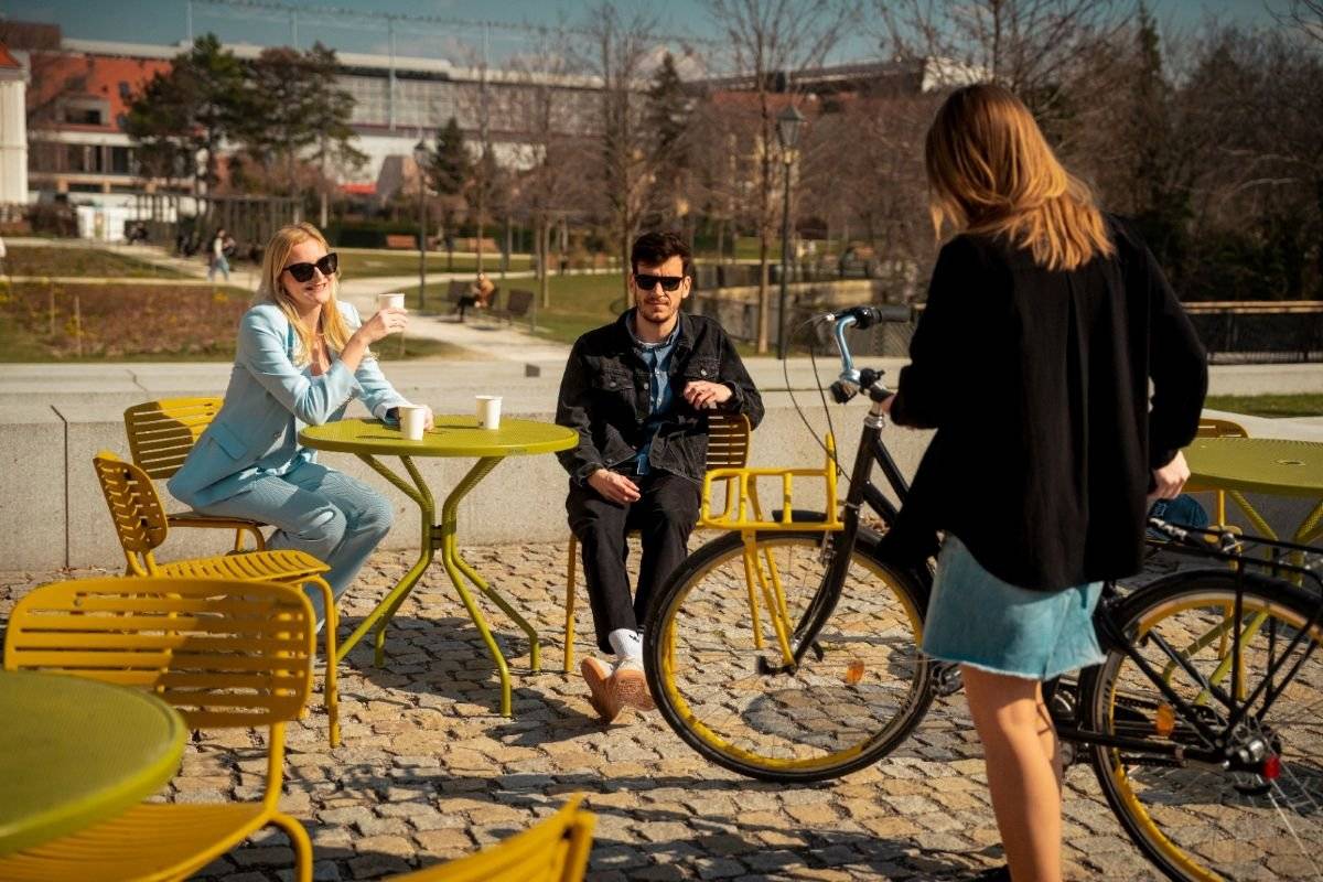 Jar v Trnave neoznamuje kalendár. Oznamujú ju žlté stoličky.     S príchodom príjemnejších dní je späť aj obľúbený mestský mobiliár, ktorý počas sezóny od jari do jesene rozjasňuje verejný priestor. Obyvatelia aj návštevníci si môžu oddýchnuť na 27 zelených stoloch a 100 žltých stoličkách rozmiestnených vo viacerých lokalitách v centre Trnavy.     Najviac stolov a stoličiek je umiestnených na Trojičnom námestí pod lipami a v okolí Sochy svätej trojice, kde si môžete vychutnať pohľad na centrum mesta z prvej rady. Ďalšie sú na Námestí SNP, Hlavnej ulici, pri Trnavskej univerzite, v Parku Bela IV., na Zelenom kríčku, Kapitulskej ulici, Námestí sv. Mikuláša, v Ružovom parku, pri hradbách aj v parčíku pri Katedrále.     Či už si prídete sadnúť na kávu, stretnúť sa s priateľmi alebo si len na chvíľu oddýchnuť počas dňa, Trnava vás pozýva spomaliť.