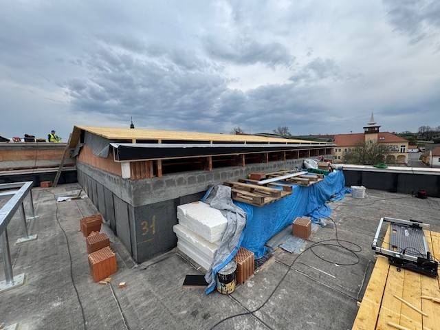 Na stavbě nového Obecního domu byl na programu další kontrolní den (za účasti projektantů, architektů, zástupců investora a zhotovitele se koná pravidelně každé úterý). Práce pokračují v souladu s harmonogramem a budova tak už dnes získává svou finální podobu.  V současnosti jsou osazena téměř všechna okna. Uvnitř jsou v plném proudu práce na elektroinstalacích, rozvodech vody a kanalizace. Část stěn je již omítnutá, zároveň se pracuje na sádrokartonových konstrukcích a příčkách. Dokončena jsou všechna betonová schodiště. Na střeše se aktuálně pracuje na pokládce finálních vrstev, včetně tepelné izolace a hydroizolačních fólií. Současně se postupně zpřesňuje a vybírá finální podoba interiérů – od detailů schodišť a podlah až po akustické řešení hlavního sálu.  Nový Obecní dům nabídne moderní a důstojné zázemí pro městskou knihovnu, informační centrum i základní uměleckou školu s akusticky upravenými učebnami a menším koncertním sálem. Součástí bude také velký multifunkční sál s kapacitou 527 míst, určený pro kulturní a společenské akce.  Celková hodnota projektu je bezmála 166 milionů korun bez DPH. Stavbu realizuje společnost MSO servis spol. s r. o. Kyjov. Dokončení je plánováno do 600 kalendářních dnů od zahájení prací (červen loňského roku). Na financování projektu se již podařilo našemu městu získat dotace ve výši 38 milionů korun, o získání dalších prostředků budeme usilovat. Aktuální podobu stavby si můžete prohlédnout v přiložené fotogalerii, vizualizaci budoucího vzhledu Obecního domu si můžete prohlédnout pod odkazem zde.