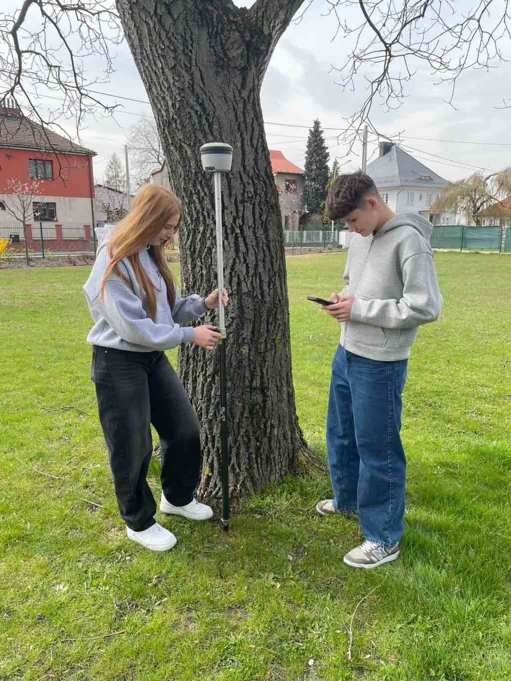 Studenti kvinty a 3.A se v hodinách cvičení z biologie věnují praktickým úlohám. Umožňuje jim to speciální náčiní sloužící ke zkoumání okolní stromové flory, které zahrnuje GNSS přijímač, ovládací a zapisovací zařízení a specializovaný software – právě to gymnáziu poskytuje Město Hlučín. Studenti zaznamenávají stáří stromů, obvod jejich kmene a jejich zdravotní stav. Díky speciální lokalizační tyči pak přesně určují jeho polohu a podílí se tak na tzv. pasportizaci městské zeleně. Ta slouží jako rozšíření a aktualizace informací, napomáhá včasné identifikaci nemocných stromů a tvorbě plánu, jak o stromy dále pečovat. „Podporujeme rozvoj praktické výuky studentů a dělá nám radost, když tím můžeme pomoci i někomu dalšímu, v tomto případě městskému odboru životního prostředí a komunálních služeb. Funguje to jako symbióza, my pomáháme městu a město zase nám,” uvedl zástupce ředitelky a učitel biologie Petr Klein. #hlucin #mestohlucin #spoluprace #mereni #gjk