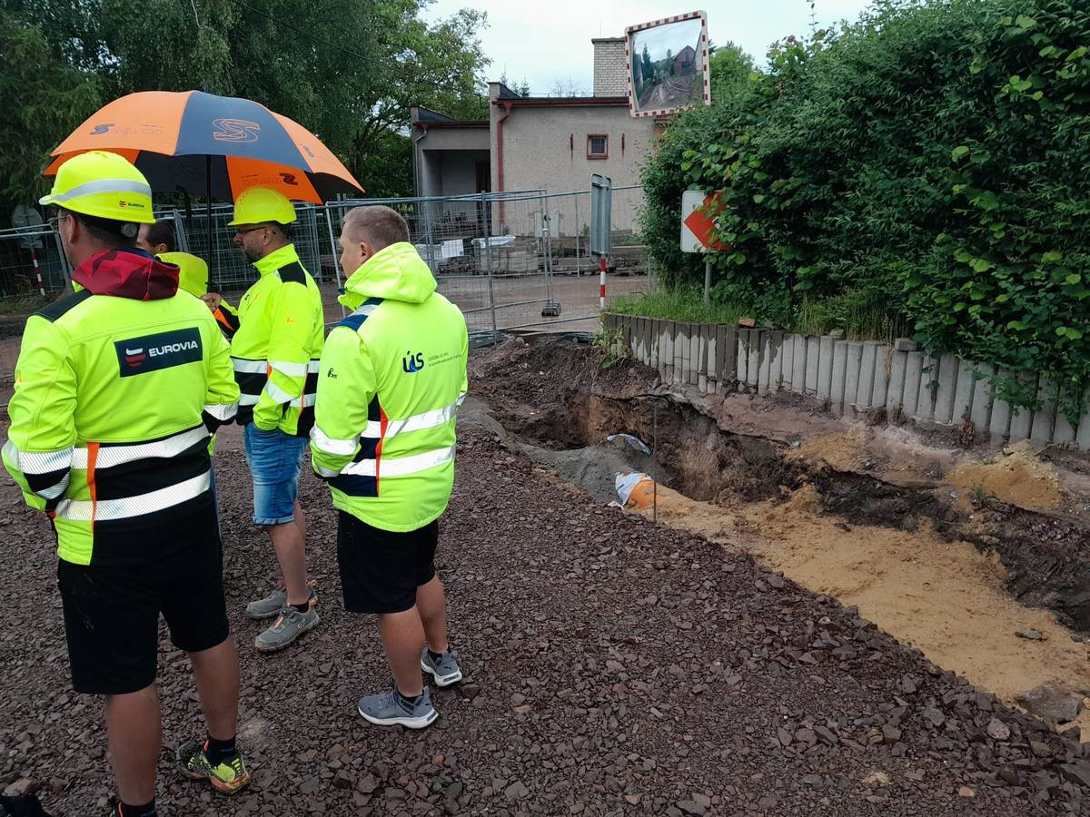 Vážení spoluobčané, stavební práce v Hronovské ulici v lokalitě U Kříže pokračují, avšak oproti původnímu harmonogramu nabrala stavba zpoždění. Důvodem jsou nepředvídatelné komplikace, které ovlivnily návaznost jednotlivých činností a zpomalily postup první etapy rekonstrukce. Kamerová prohlídka stávající dešťové kanalizace odhalila nevyhovující technický stav potrubí v levém jízdním pruhu. Původní betonové potrubí je proto postupně odstraňováno a nahrazováno novým. Tato nutná výměna představuje časově i finančně náročnou vícepráci. Další komplikace se objevily v dolní části úseku první etapy, kde bylo po odstranění podkladních vrstev zjištěno zvodnělé podloží. To muselo být sanováno, aby byla zajištěna dlouhodobá stabilita konstrukce vozovky. K prodloužení termínu dokončení přispívá také nepříznivé počasí, které opakovaně omezuje možnost provádět technologicky navazující práce. Předpokládaný termín pokládky asfaltových vrstev je nyní stanoven na období 22.–26. června 2026. O dalším postupu budou občané průběžně informováni.  Bc. Stanislav Řezníček, DiS. -  starosta města                                   Ing. Jaroslava Valentová - Údržba silnic Královéhradeckého kraje a.s.