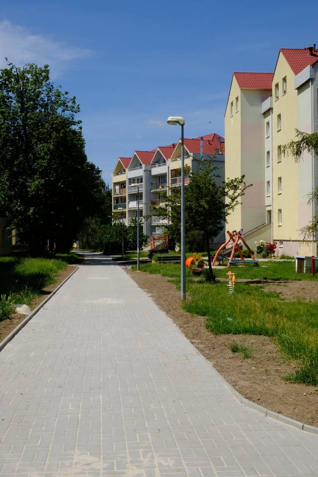 Dokončili jsme rekonstrukci chodníku na sídlišti Rohožník. Stavební práce probíhaly od začátku března a jejich cílem bylo zlepšit technický stav pěších komunikací, zvýšit bezpečnost pohybu chodců a zajistit bezbariérové užívání veřejného prostoru. Rekonstrukce zahrnovala zejména:  pokládku 1 651,5 m² šedé betonové zámkové dlažby, instalaci 10,6 m² reliéfní červené dlažby pro nevidomé a 10,2 m² přídlažby, obnovu 955,7 metrů obrubníků, lokální úpravy asfaltových ploch, sanaci podloží a výměnu nevyhovujících podkladních vrstev, zřízení nových konstrukčních vrstev ze štěrkodrtí a betonu, pokládku geotextilií a drenážních prvků, úpravy kanalizačních vpustí, šachet, hydrantů a armatur, odvodnění čistících zón, zakrytí vstupů do kolektorů a výměnu poklopů, terénní úpravy, doplnění ornice a zatravnění okolních ploch, reliéfní prvky pro nevidomé.  Součástí realizace byla rovněž dopravní opatření během výstavby, geodetické zaměření stavby, vytyčení inženýrských sítí, zkoušky hutnění a únosnosti konstrukcí. Celkové náklady na realizaci činily 10 317 194 Kč včetně DPH. Dokončená rekonstrukce přináší obyvatelům Rohožníku bezpečnější, komfortnější a esteticky kvalitnější pěší trasu, která bude sloužit mnoho dalších let. Ve fotogalerii se můžete podívat na proměnu chodníku před a po rekonstrukci.  Před rekonstrukcí   Po rekonstrukci
