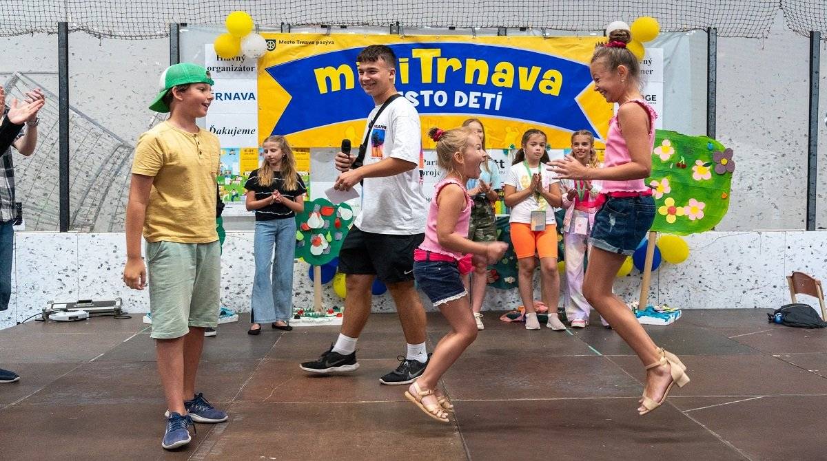 Letné prázdniny v Trnave budú opäť patriť deťom. Obľúbený projekt miniTrnava – mesto detí sa vracia na Mestský zimný štadión, aby od 6. do 17. júla 2026 ponúkol malým občanom priestor na hru, prácu aj nezávislosť.  V ôsmom ročníku preberá po mestskom úrade ako organizátor štafetu mestská organizácia GenT. Tohtoročnou najväčšou novinkou bude slávnostné finále pre rodičov detí aj celú verejnosť a odvážne plány s nahliadnutím do sveta.  Svet, kde vládnu deti – miniTrnava nie je len obyčajná prázdninová hra. Je to fungujúci mestský ekosystém určený deťom od 8 do 15 rokov. Na dva júlové týždne sa tréningová hala zimného štadióna na Spartakovskej ulici zmení na pulzujúcu metropolu s vlastnou radnicou, bankou, univerzitou, novinami aj manufaktúrou. Deti tu nie sú len návštevníkmi – sú občanmi. Sami si hľadajú prácu na úrade práce, zarábajú trnky (miestnu menu), platia dane, študujú na univerzite alebo rozhodujú o smerovaní mesta v demokratických voľbách.  „V miniTrnave dávame deťom to najcennejšie – dôveru, priestor a slobodu skúšať veci po svojom. Učia sa zodpovednosti za vlastné rozhodnutia, spolupráci aj tomu, ako funguje komunita. To všetko v bezpečnom hernom prostredí,“ uviedla koordinátorka miniTrnavy z mestskej organizácie GenT Soňa Sutjaginsová.  Program a osvedčené pravidlá Pravidlá hry zostávajú verné úspešným predchádzajúcim ročníkom. Vstup je pre deti bezplatný a nie je potrebná žiadna registrácia vopred. Stačí prísť na „matriku“, vybaviť si preukaz občana a zapojiť sa do kolobehu mesta. Každý pracovný deň od 8.00 do 14.30 h sa deti môžu stať remeselníkmi, redaktormi, policajtmi či záhradníkmi.  Novinka 2026: Piatok patrí všetkým Tento rok prináša miniTrnava výnimočný moment pre celú komunitu. V posledný deň projektu, v piatok 17. júla od 15.00 h, sa brány minimesta otvoria dokorán pre širokú verejnosť – rodičov, starých rodičov a priateľov. Odporúčame prísť už o 14.30 h, aby bolo možné začať načas. Bude to čas osláv, keď deti prevezmú iniciatívu a ukážu dospelým svet, ktorý dva týždne budovali. Rodičia si budú môcť pozrieť aké úsilie deti venovali miniTrnave a priamo podporiť ich “podnikanie”. Všetci návštevníci sa môžu tešiť na:  záverečný trh výrobkov: Deti budú v roli predajcov ponúkať unikáne predmety, ktoré vlastnoručne zhotovili v manufaktúre. prehliadku talentov: Malí občania predvedú nacvičené choreografie, divadelné čísla a iné vystúpenia. osobných sprievodcov: Deti môžu svojej rodine ukážať svoje obľúbené zákutia mesta a miesta, kde „pracovali“. Je to príležitosť užiť si posledné spoločné chvíle v miniMeste predtým, než sa jeho brány na rok zatvoria.  Vízia do budúcna Organizátori aktuálne pripravujú koncept Ambasády miniTrnavy. Jej cieľom je vytvoriť inkluzívny priestor pre deti, ktoré možno nehovoria plynule po slovensky, a uľahčiť im začlenenie do komunity malého mesta. Zároveň má ambasáda slúžiť ako most k iným podobným „minimestám“ vo svete. Informácia k doprave Z dôvodu konania podujatia bude od 1. do 17. júla uzatvorená časť parkoviska pre Mestskom zimnom štadióne (v časti za oplotením) a nebude tu možné parkovať. Ďakujeme za pochopenie.