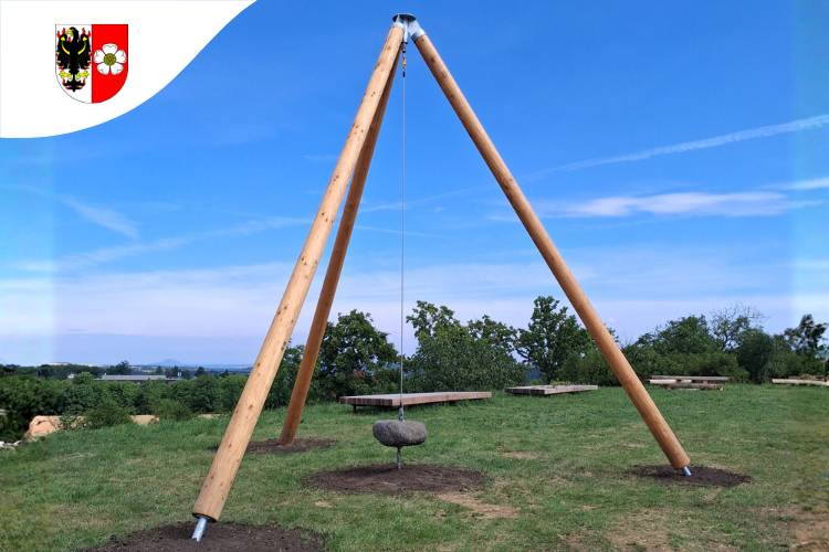 Pokud se vydáte na procházku na Holý vrch po Stezce Čeňka Rýznera, čeká vás nová zajímavost. Objevil se zde originální landartový artefakt ve formě archetypálního tripodu s kyvadlem, který slouží nejen jako socha, ale také jako interaktivní herní prvek.