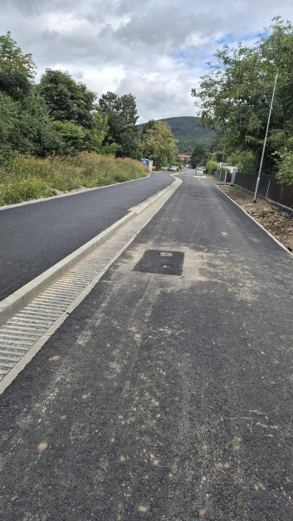Při čtvrteční kontrole probíhající rekonstrukce ulice Na Hrázi odhalili zástupci města poškození, která vznikla při nedávné pokládce asfaltu. Vedení města k situaci zaujalo nekompromisní postoj a se zhotovitelem nyní intenzivně jedná. Radnice striktně odmítá pouze lokální či dílčí opravy a trvá na komplexní nápravě – zničené části se musí rovnou předělat. Cílem města je, aby bylo hotové dílo naprosto v pořádku už při prvním předání. Ke vzniku škod, mezi které patří mimo jiné vyvalené obruby, došlo 13. července během pokládky a válcování asfaltového povrchu. Již na pátek 24. července proto město svolalo schůzku se zhotovitelem a zástupci společnosti, která asfalt pokládala, v rámci mimořádného kontrolního dne. Na tomto jednání se bude detailně probírat rozsah problémů, a především konkrétní řešení a postup kompletního předělání poškozených úseků. První etapa rekonstrukce odstartovala 4. května a podle původního harmonogramu měla skončit do konce července. O případném posunu termínu dokončení prací bude město informovat. Tento článek budeme bezprostředně po skončení schůzky se zhotovitelem aktualizovat. O projektu rekonstrukce ulice  Na Hrázi Tato stavba patří mezi klíčové investice města v roce 2026. Celý projekt je rozdělen do čtyř etap, z nichž první dvě odstartovaly už letos. První etapa zahrnuje úsek od občerstvení po křižovatku s ulicí V Dolině, druhá pak část ulice Na Hrázi směrem k odbočce k malé vodní elektrárně a také ulici Pod Haldou, která je o prázdninách neprůjezdná. Výsledkem rekonstrukce bude oprava vozovky, chodníků a parkovacích stání, zklidnění dopravy i vznik nové společné stezky pro pěší a cyklisty na straně směrem k Berounce. Návrh rovněž pamatuje na řešení hospodaření s dešťovou vodou a celkové zvýšení bezpečnosti pro chodce, cyklisty i řidiče.