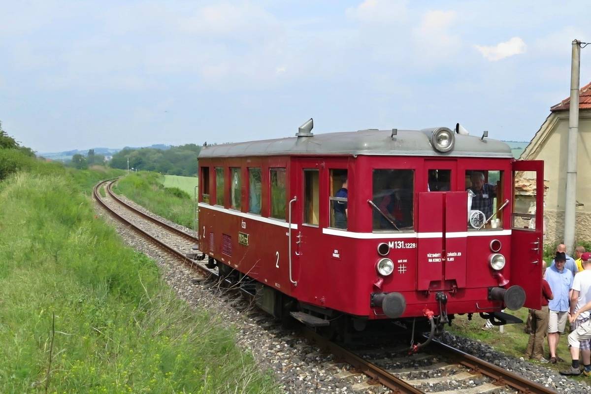 Malebná podbrdská železnice, která dodnes spojuje údolí Berounky s Lochovicemi, slaví své 125. výročí. Když na přelomu srpna a září roku 1901 projel po trati ze Zadní Třebaně přes Liteň do Lochovic první oficiální vlak, znamenalo to pro celý region obrovský skok kupředu. Místní dráha, které nikdo neřekne jinak než „Liteňka“, se stala klíčovou tepnou pro dopravu zboží i dělníků a dodnes si zachovala své neopakovatelné kouzlo.   Odvážný plán podbrdských vizionářů   Cesta k realizaci 26,5 kilometru dlouhé trati nebyla jednoduchá. Myšlenku začali už v roce 1892 prosazovat místní velkostatkáři, především E. Greif z Hostomic a Josef Šebestián Daubek z Litně. Trvalo dlouhých osm let, než se podařilo vyjednat koncese, získat státní garance a překonat spory o přesné trasování kolejí. Když se však v roce 1900 stavební firma J. Kubíček z Královských Vinohrad konečně pustila do díla, projevila nevídanou rychlost. K položení celé trati v náročném terénu s výrazným stoupáním jí stačil pouhý rok. Výstavba 26,5 kilometru dlouhé železnice tehdy přišla na 2 786 400 rakouských korun, což představovalo na počátku 20. století mimořádně vysokou investici do rozvoje celého regionu. První oficiální vlak vyrazil na cestu 30. srpna 1901 a pravidelný provoz pro veřejnost začal hned 1. září.   Převýšení, výhledy a historická úvrať   „Liteňka“ patří k nejromantičtějším jednokolejným tratím v České republice. Vlaky jedoucí ze Zadní Třebaně musí na své trase překonat převýšení 162 metrů, přičemž maximální stoupání dosahuje 26,3 promile. Technickou zajímavostí trati byla po dlouhá léta úvraťová stanice Liteň, kde vlaky měnily směr jízdy. Právě tato provozní zvláštnost dodávala cestování po trati jedinečný charakter a dodnes patří mezi zajímavosti, které železniční nadšenci oceňují.   Výročí připomeneme jízdami legendárního „Hurvínka“   Významné 125. výročí zahájení provozu na trati připomeneme v sobotu 5. září 2026 stylově – na koleje Liteňky se vrátí legendární motorový vůz řady M 131.1, známý pod přezdívkou „Hurvínek“.   Tento ikonický motorový vůz vyráběly v letech 1948 až 1956 podniky Tatra Kopřivnice a Vagónka Studénka. Celkem vzniklo více než 500 vozů, které se staly symbolem poválečné obnovy regionálních tratí. Na českých a slovenských lokálkách sloužily především od konce 40. let až do 80. let 20. století, na některých méně vytížených tratích dokonce ještě déle. Charakteristický hluboký „tatrovácký“ zvuk šestiválcového motoru, jednoduchý interiér s dřevěnými lavicemi u nejstarších vozů a nezaměnitelný vzhled dodnes vyvolávají nostalgické vzpomínky několika generací cestujících.   Jízda historickým „Hurvínkem“ po malebné podbrdské krajině nabídne jedinečnou možnost zažít atmosféru cestování z dob, kdy podobné motorové vozy byly na místních tratích každodenním dopravním prostředkem. Věříme, že se stane jedním z hlavních lákadel letošního Loučení s létem a potěší nejen železniční fanoušky, ale také rodiny s dětmi a všechny milovníky historie.   Podrobnosti o aktuálním jízdním řádu historického vlaku i informace o předprodeji jízdenek budeme průběžně zveřejňovat na webových stránkách obce a KD Liteň. Doporučujeme proto sledovat aktuality, aby vám neunikly žádné novinky ani termín zahájení prodeje jízdenek.   Pohled do budoucna I po 125 letech má tato regionální dráha své pevné místo v integrované dopravě. V posledních letech prošla trať pod správou Správy železnic nezbytnými opravami kolejového svršku a mostních konstrukcí, které jí zajišťují bezpečný provoz do dalších let. „Liteňka“ tak i v 21. století spolehlivě vozí turisty za krásami Českého krasu i místní obyvatele za prací a školami.   Letošní výročí je zá