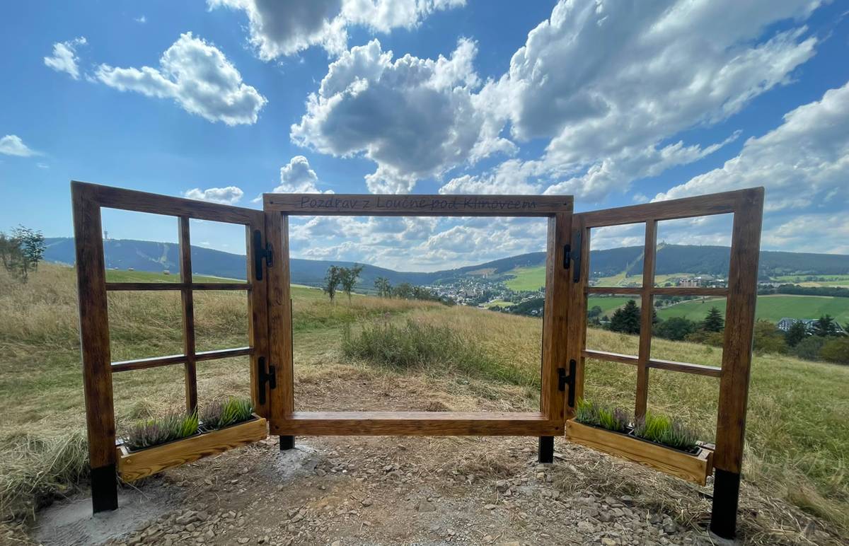 Někteří z vás už si ho možná všimli. V Loučné pod Klínovcem máme nový fotopoint! Najdete ho u vrtulí za hřbitovem, na místě s krásným výhledem na Klínovec i Fichtelberg. A protože má podobu okna, můžeme se společně podívat skrze naše nové „Okno do Krušnohoří“.  Už jste ho navštívili? 📷 Budeme moc rádi, když se s námi podělíte o své fotografie – pošlete nám je nebo je přidejte do komentářů pod příspěvek. A nezapomeňte bedlivě sledovat naše stránky… 👀 Možná se totiž kolem našeho Okna do Krušnohoří brzy objeví i nějaká soutěž.  Tak kdo bude mít první fotku? 😊