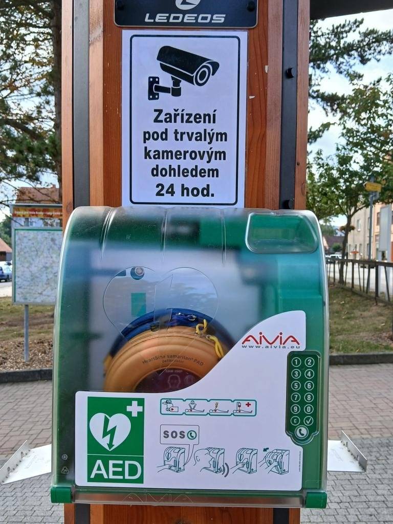 AED může zachránit lidský život   V Blovicích je nově k dispozici veřejně přístupný automatický externí defibrilátor (AED). Ve spolupráci s hasiči Blovice jsme jej umístili na veřejný dobíjecí stojan na Masarykově náměstí. AED může v případě náhlé zástavy srdce pomoci zachránit lidský život v prvních, rozhodujících minutách před příjezdem zdravotnické záchranné služby. Jak postupovat v případě nouze?  Na skříňce AED stiskněte tlačítko telefonu. Spojíte se s dispečinkem Zdravotnické záchranné služby. Nahlaste situaci a uveďte, že se nacházíte u AED na Masarykově náměstí v Blovicích. Dispečer vám sdělí čtyřmístný kód. Kód zadejte na klávesnici skříňky a potvrďte tlačítkem ✓. Skříňka se odemkne a AED můžete vyjmout. Přesuňte se k pacientovi, přístroj zapněte a řiďte se jeho hlasovými a vizuálními pokyny.  Součástí označení AED je také QR kód s videonávodem k jeho použití. Upozornění: Prostor, kde je AED umístěn, je nepřetržitě monitorován kamerovým systémem. Věříme, že tento přístroj nebude nikdy potřeba. Jeho dostupnost v centru města však představuje důležitý krok ke zvýšení bezpečnosti obyvatel i návštěvníků Blovic. V případě náhlé zástavy srdce totiž může každá sekunda znamenat rozdíl. Město Blovice děkuje všem, kteří se na realizaci tohoto projektu podíleli.